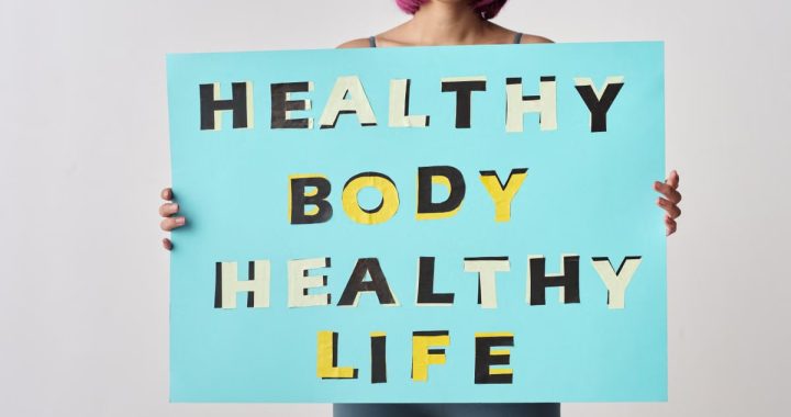 A woman holds a motivational poster advocating a healthy body and life for wellness.