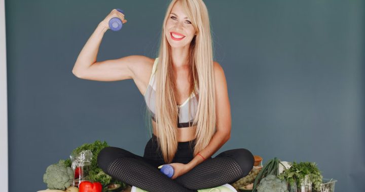 Woman lifting a small dumbbell while surrounded by fresh vegetables, embodying health and fitness.