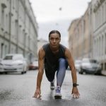 Woman in activewear poised for a run on a city street, symbolizing fitness and determination.